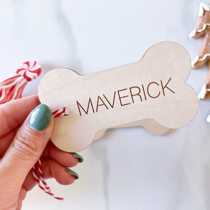Custom Pet Name Christmas Ornament (Bone shape) being held up against a Christmas background