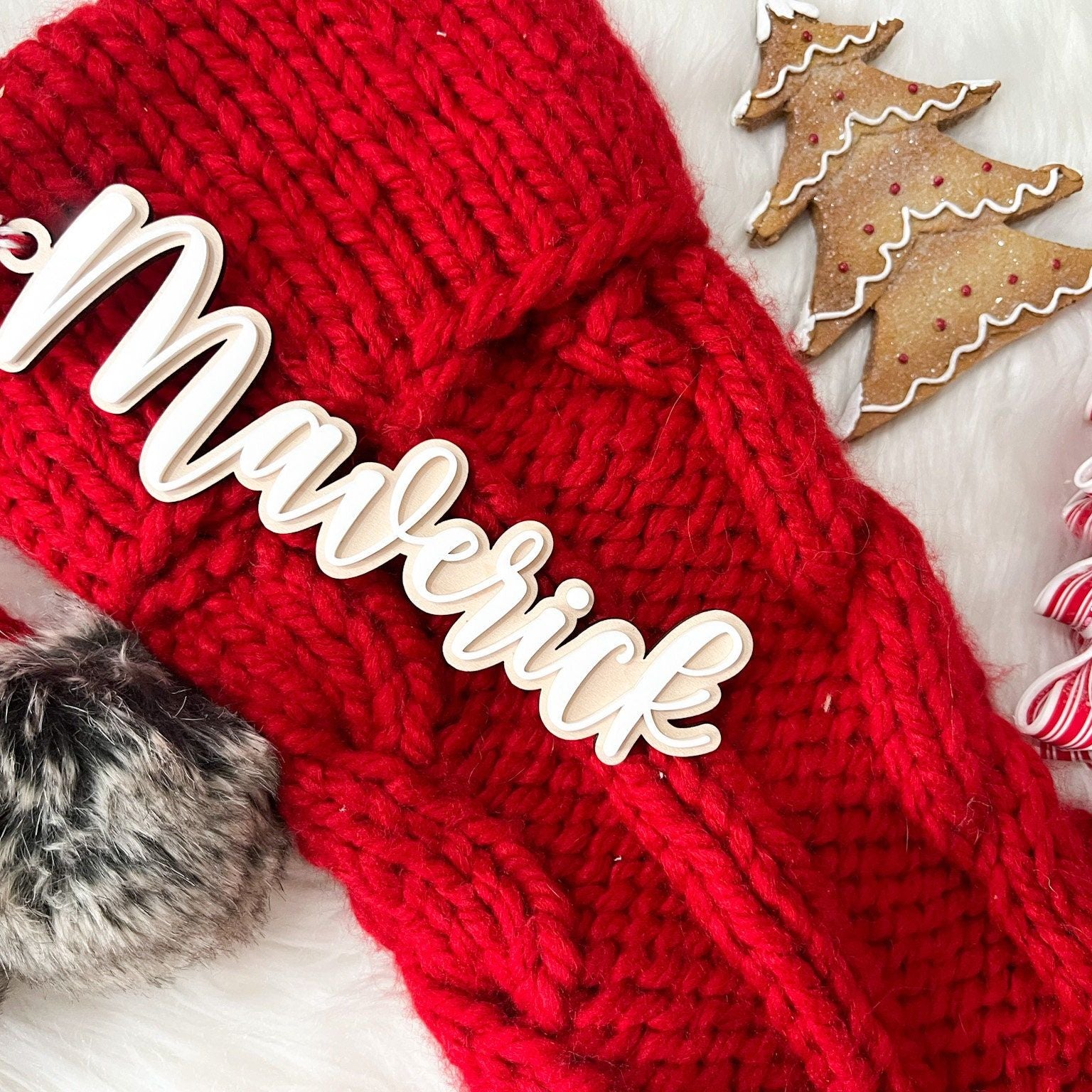 Close-up of 3D Layered Name Christmas Tag ("Maverick") with white acrylic on wood, hanging from a red knit stocking.
