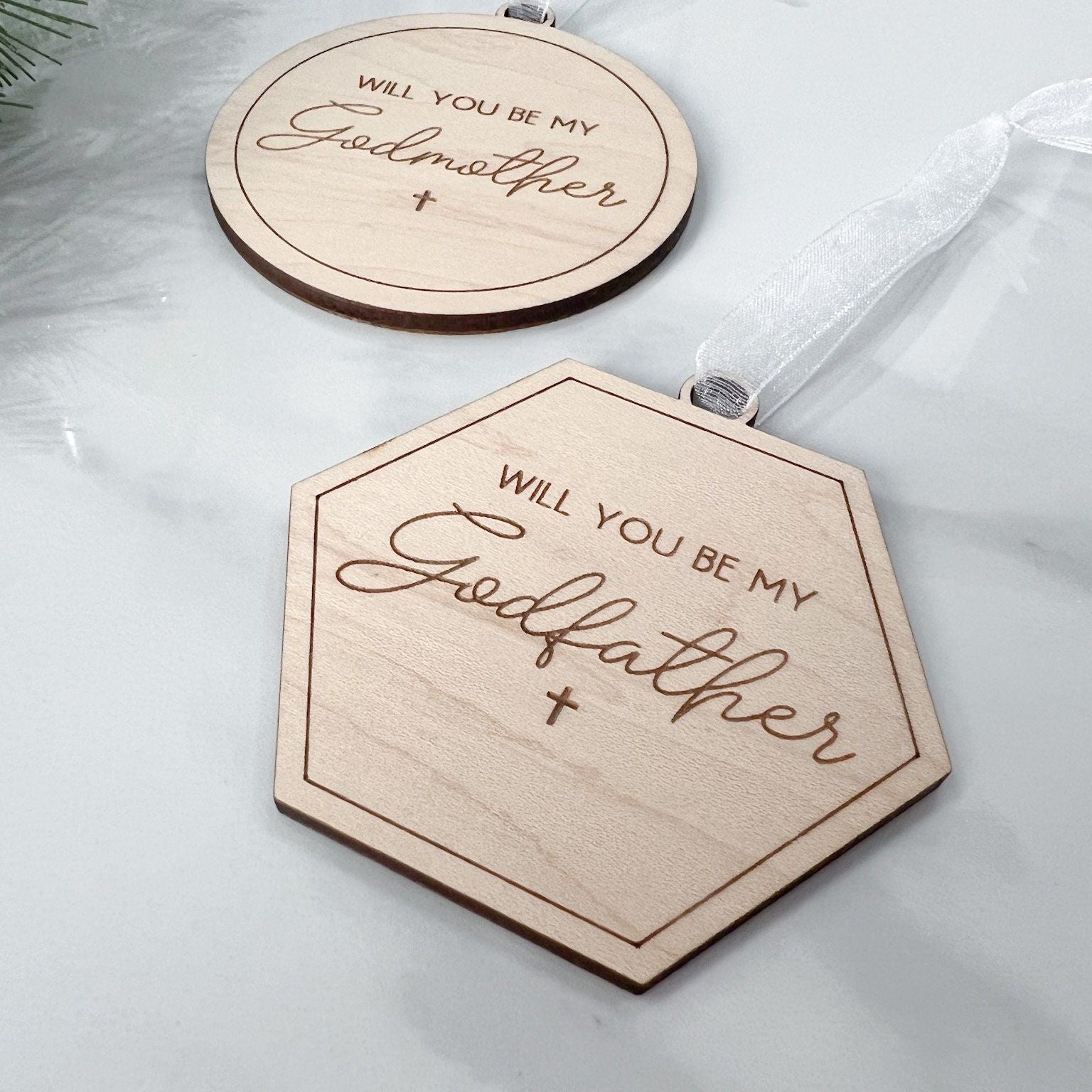 Close-up of laser-cut maple plywood wood keepsakes, used as a godparent proposal gift and baptism announcement tag.