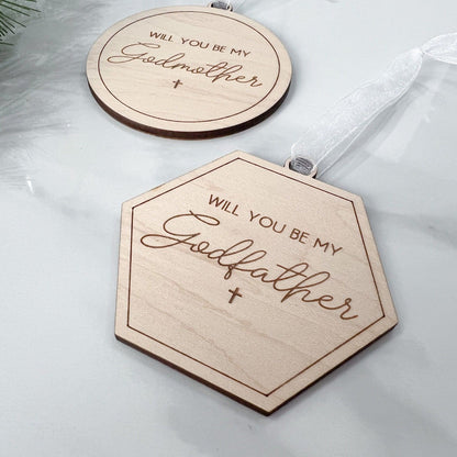 Close-up of laser-cut maple plywood wood keepsakes, used as a godparent proposal gift and baptism announcement tag.
