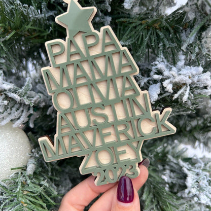 Hand holding the Family Heirloom Ornament, showcasing the thickness of the maple plywood base and the dimensional look of the 3D names.