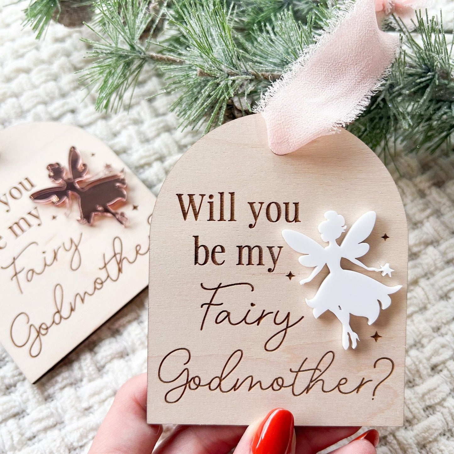 Hand holding the Layered Acrylic Fairy Ornament, highlighting its size (3.2 x 3.9 inches) and use as a unique godmother announcement.