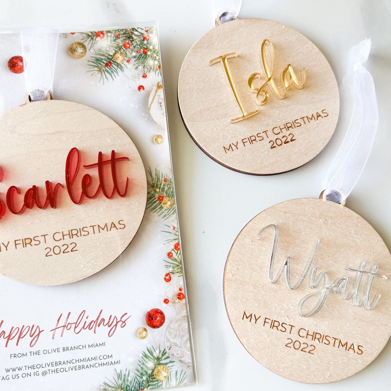 Group of three First Christmas Ornaments showing the different acrylic color choices (red, gold, silver) and the round wood shape.