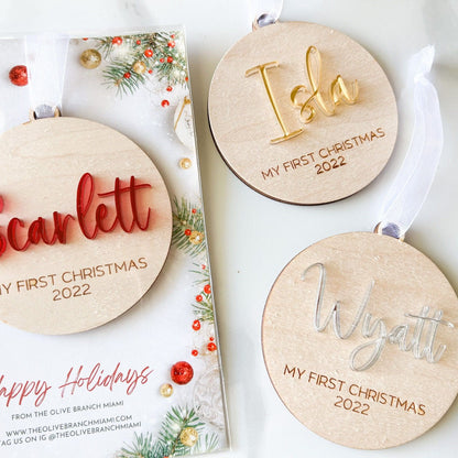 Group of three First Christmas Ornaments showing the different acrylic color choices (red, gold, silver) and the round wood shape.