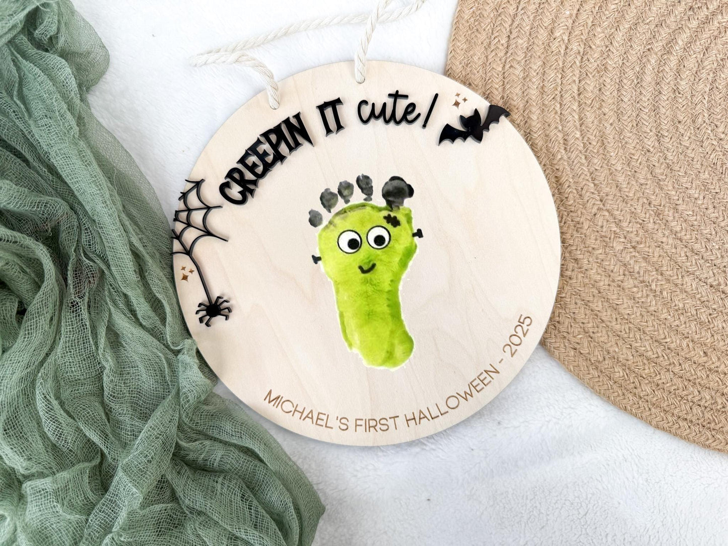 Lifestyle view of the Halloween Footprint Sign styled with seasonal decorations and baby photo props.