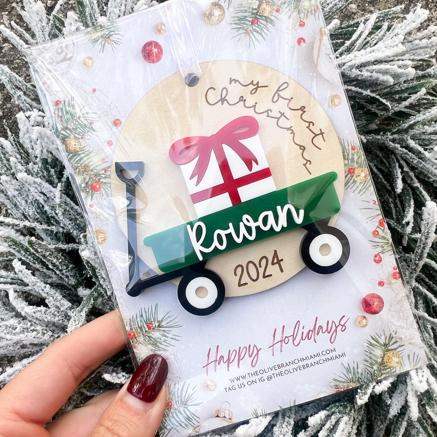 Personalized Wagon Christmas Ornament featuring the "My First Christmas" saying and a layered name in white acrylic, showing a green wagon color choice in packaging.