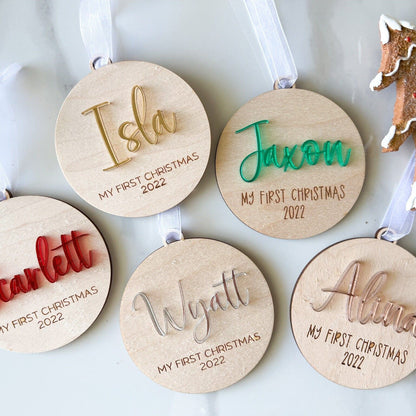 Group of five First Christmas Ornaments showing the different acrylic color choices (red, green, gold, silver) and the round wood shape.