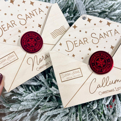 Hand holding the Wooden Christmas Wish List Ornament, showing the texture of the maple plywood and the delicate envelope shape.
