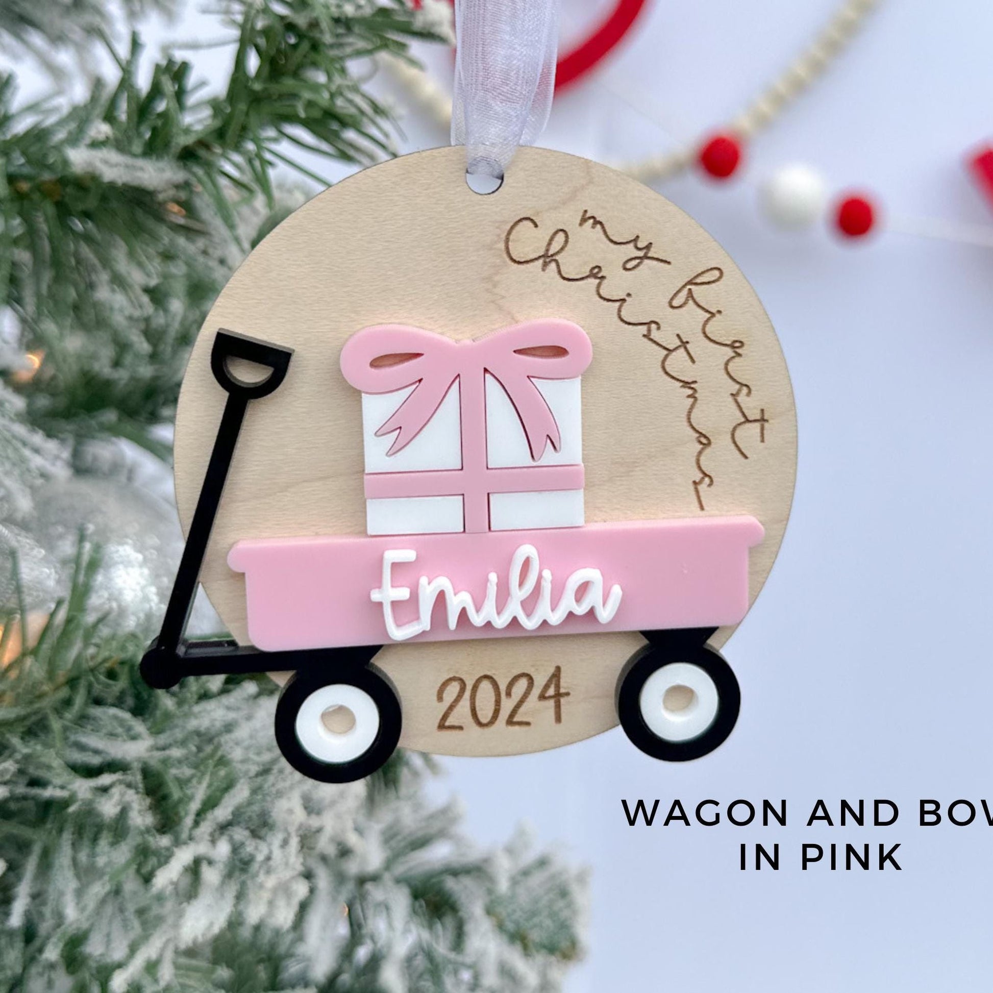 Personalized Wagon Christmas Ornament featuring the "My First Christmas" saying and a layered name in white acrylic, showing a pink wagon and bow color choice.
