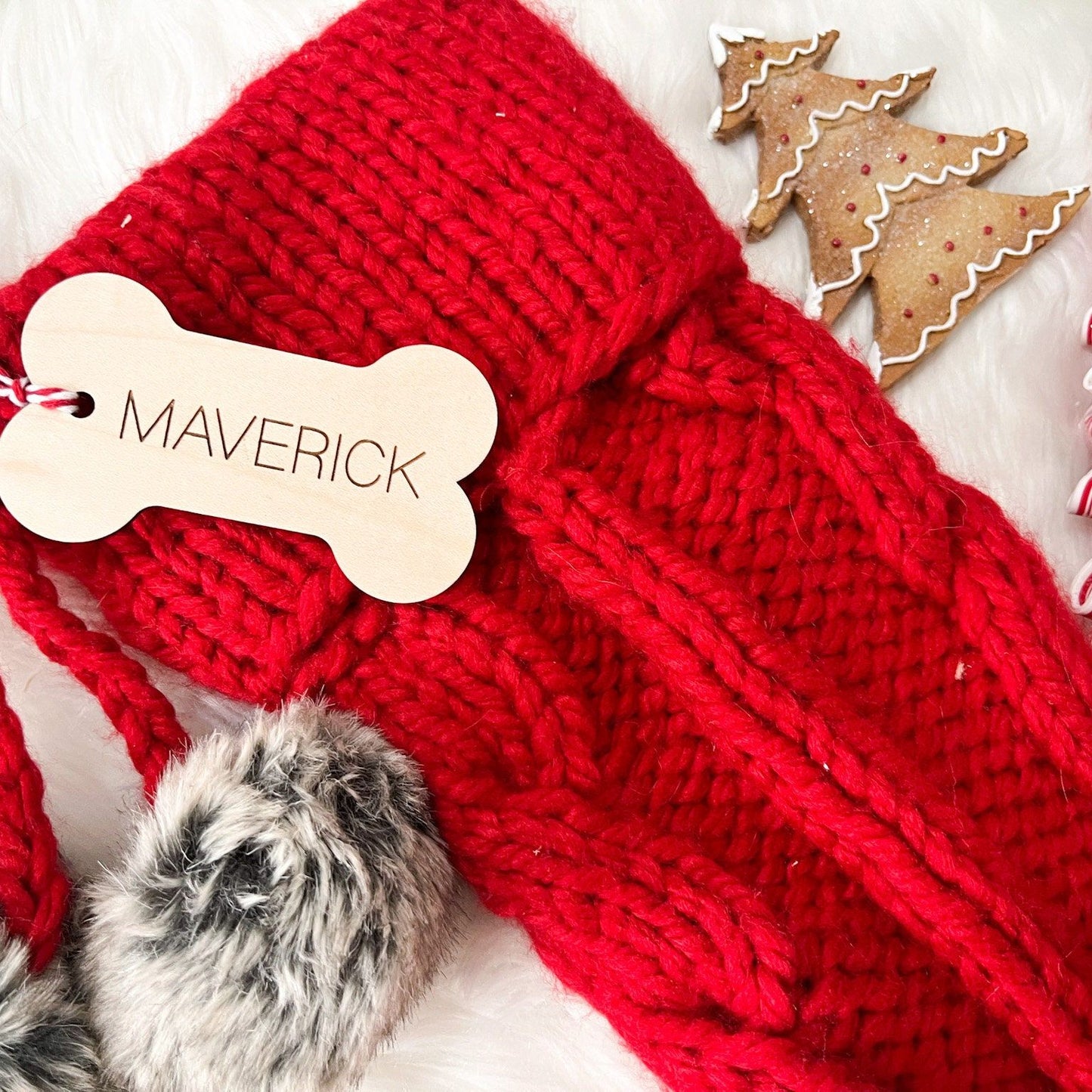 Wooden Dog Bone Stocking Tag with "Maverick" engraved, shown hanging from a red stocking with fuzzy trim.
