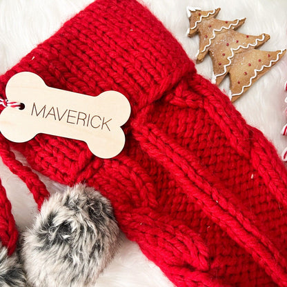 Wooden Dog Bone Stocking Tag with "Maverick" engraved, shown hanging from a red stocking with fuzzy trim.
