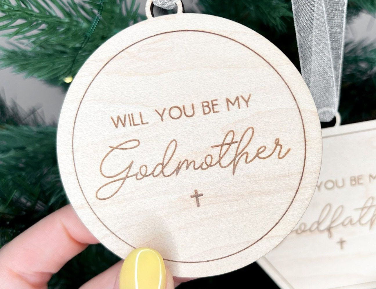 Close-up of laser-cut maple plywood wood keepsakes, used as a godparent proposal gift and baptism announcement tag.