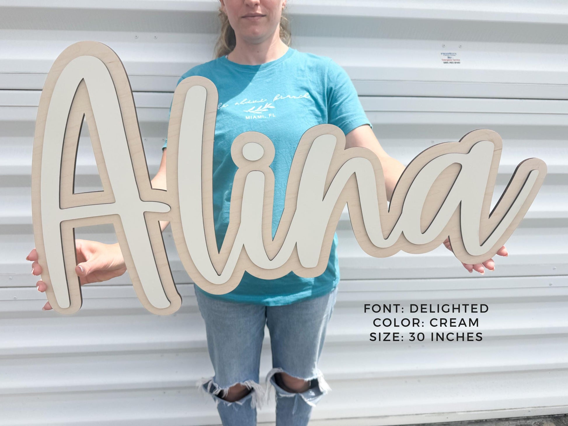 Big layered wooden nursery sign spelling "Alina" in a cursive font. The sign is cream-colored with a light beige outline and measures 30 inches in length. The font is "Delighted".
