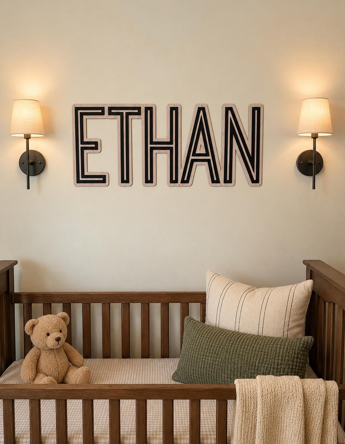 Modern personalized wooden nursery name sign displayed above a crib in a neutral nursery with warm wood furniture, custom baby name wall decor and contemporary layered lettering.