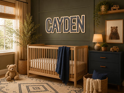 Modern personalized wooden name sign displayed above a crib in a luxury nursery with dark green accent wall, warm wood furniture, and custom layered lettering.